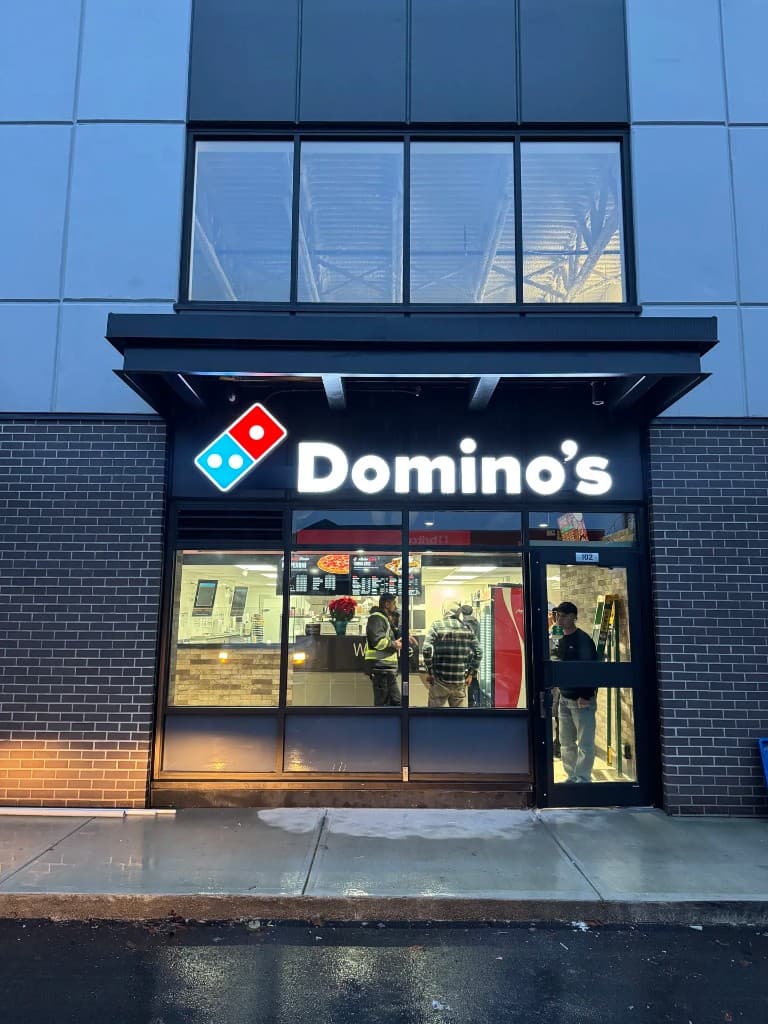 Domino's Pizza commercial storefront exterior at dusk with illuminated signage
