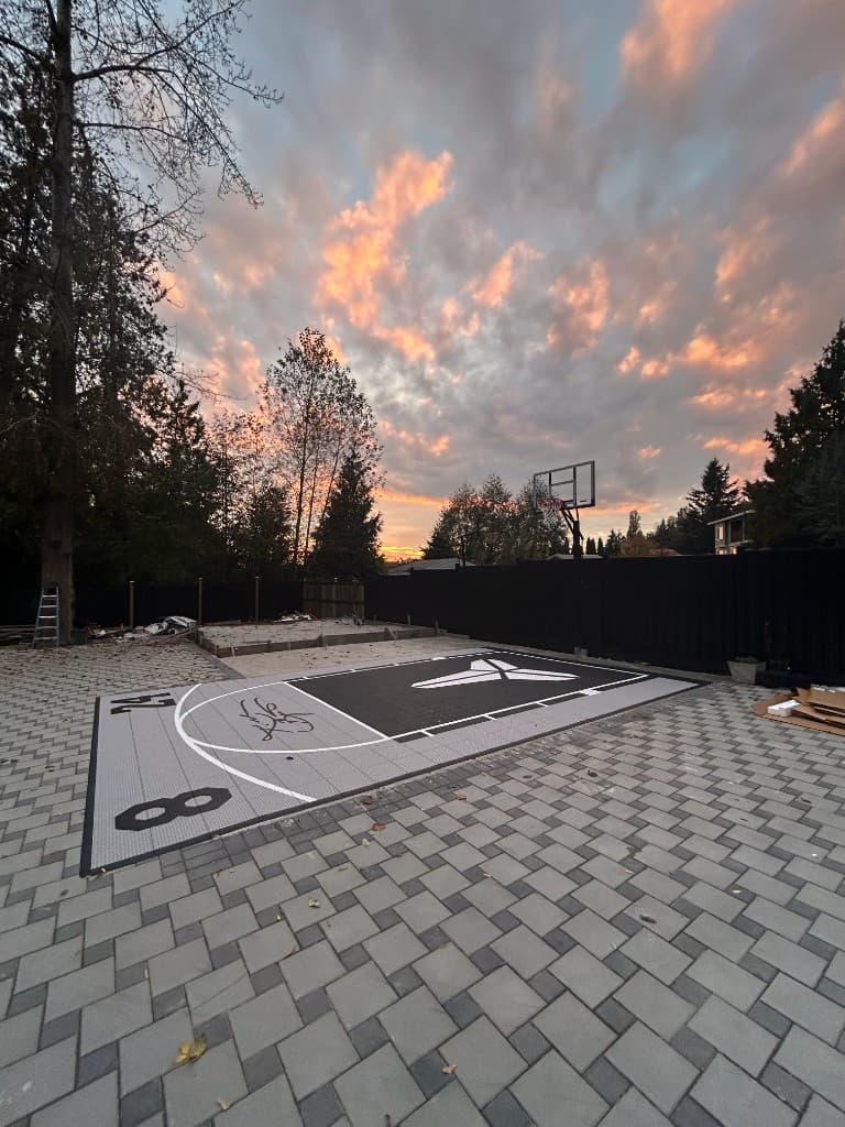 Custom backyard basketball half-court with modular surfacing at sunset
